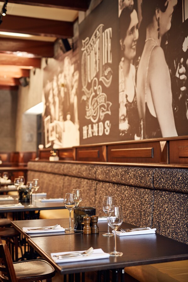 A restaurant interior with tables set for dining, a large poster on the wall, and a textured wall behind the seating area. - Hotel de Lindeboom (Den Burg)
