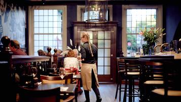 A restaurant interior with wooden tables, chairs, and a bar area.