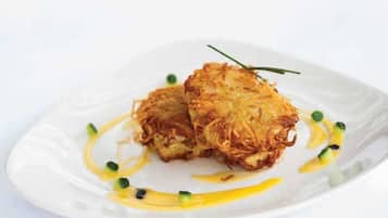 Dos tortitas crujientes y doradas sobre un plato blanco, con salsa y guarnición verde.