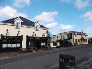 A row of buildings with signs for 'Daly's Inn' and 'Brady's Boindre' offering a guesthouse, bar, and eatery. - Dalys Inn (Donore)