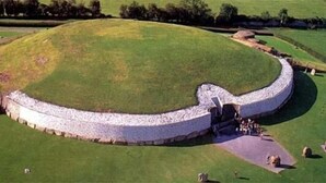 Una estructura circular de piedra con un interior cubierto de hierba, rodeada por un muro de piedra.