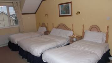 Una habitación de hotel con dos camas individuales, una mesita de noche pequeña con un teléfono y una ventana con cortinas.