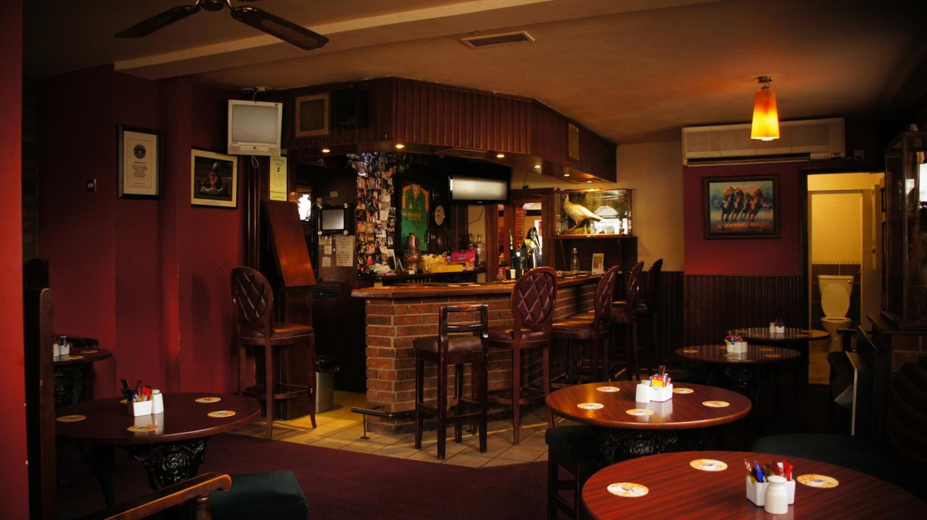 A cozy bar area with wooden furniture, a brick counter, and a television mounted on the wall.