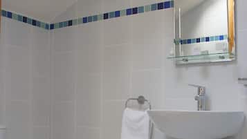 A bathroom with a toilet, a sink, and a shower area.