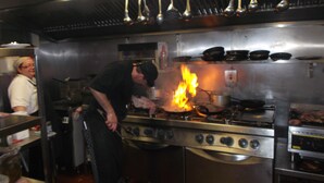 Una cocina con estufa, ollas y sartenes.