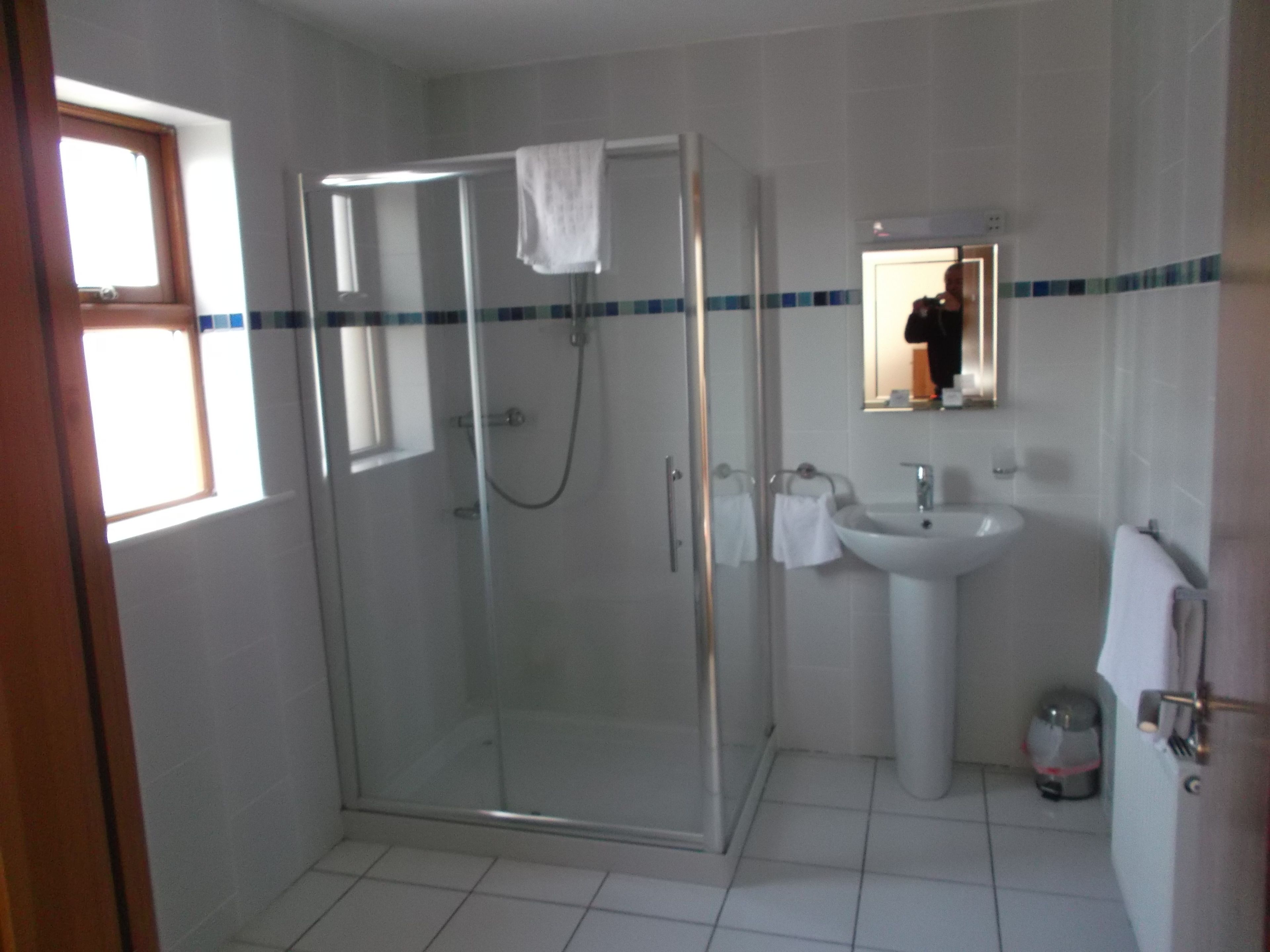 A bathroom with a glass-enclosed shower, a sink, and a mirror.