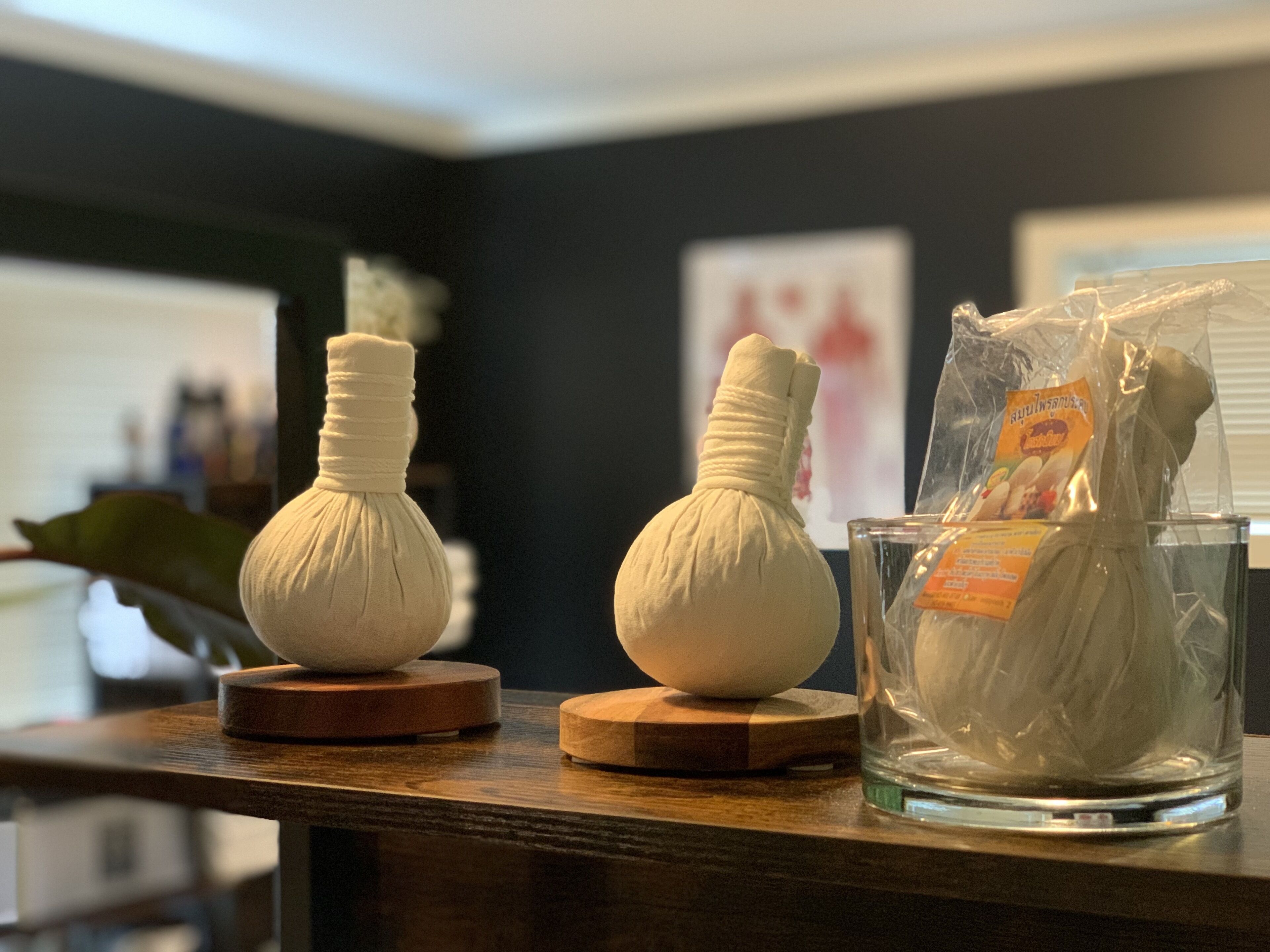Two white, bulb-shaped objects on wooden stands, a glass container with a label, and a plant in the background.