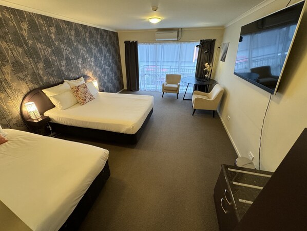 A hotel room with two beds, a desk, a chair, and a large window with a view. - BKs Premier Motel Palmerston North (Palmerston North)