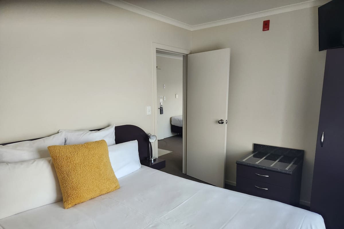 A hotel room with a bed, a nightstand, a wardrobe, and a mirror.