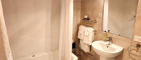 A bathroom with a bathtub, a sink, a mirror, and a towel rack.