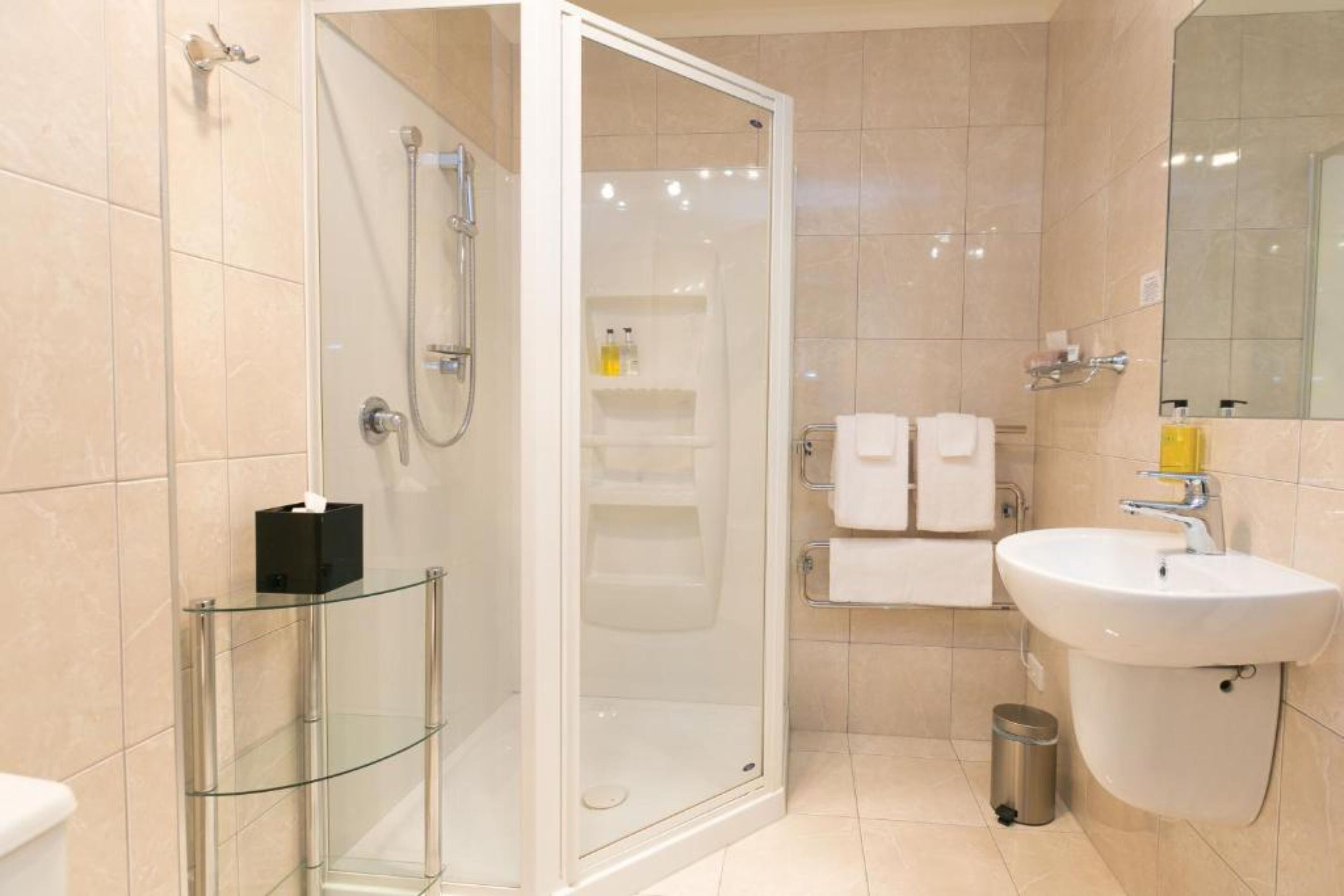 Un baño moderno con cabina de ducha de vidrio, un lavamanos y un espejo.