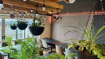 A modern interior with hanging plants, a wooden ceiling, and a striped wall.