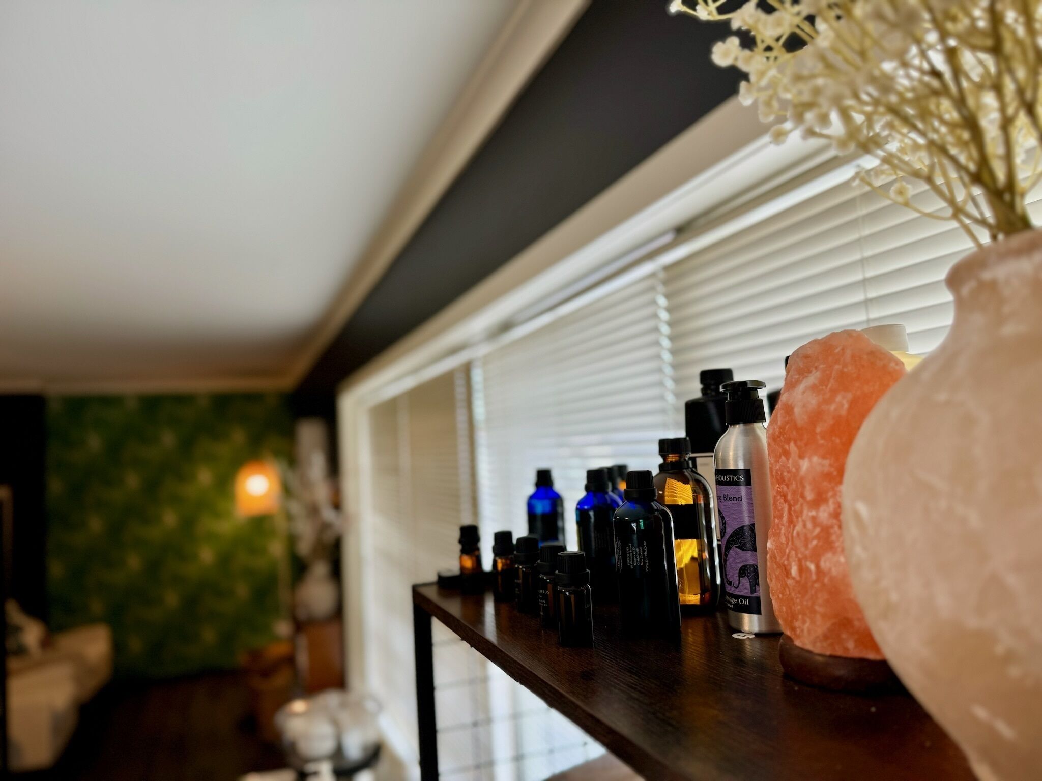 A shelf with various bottles, likely containing toiletries or personal care products, in a room with a window and a green wall.