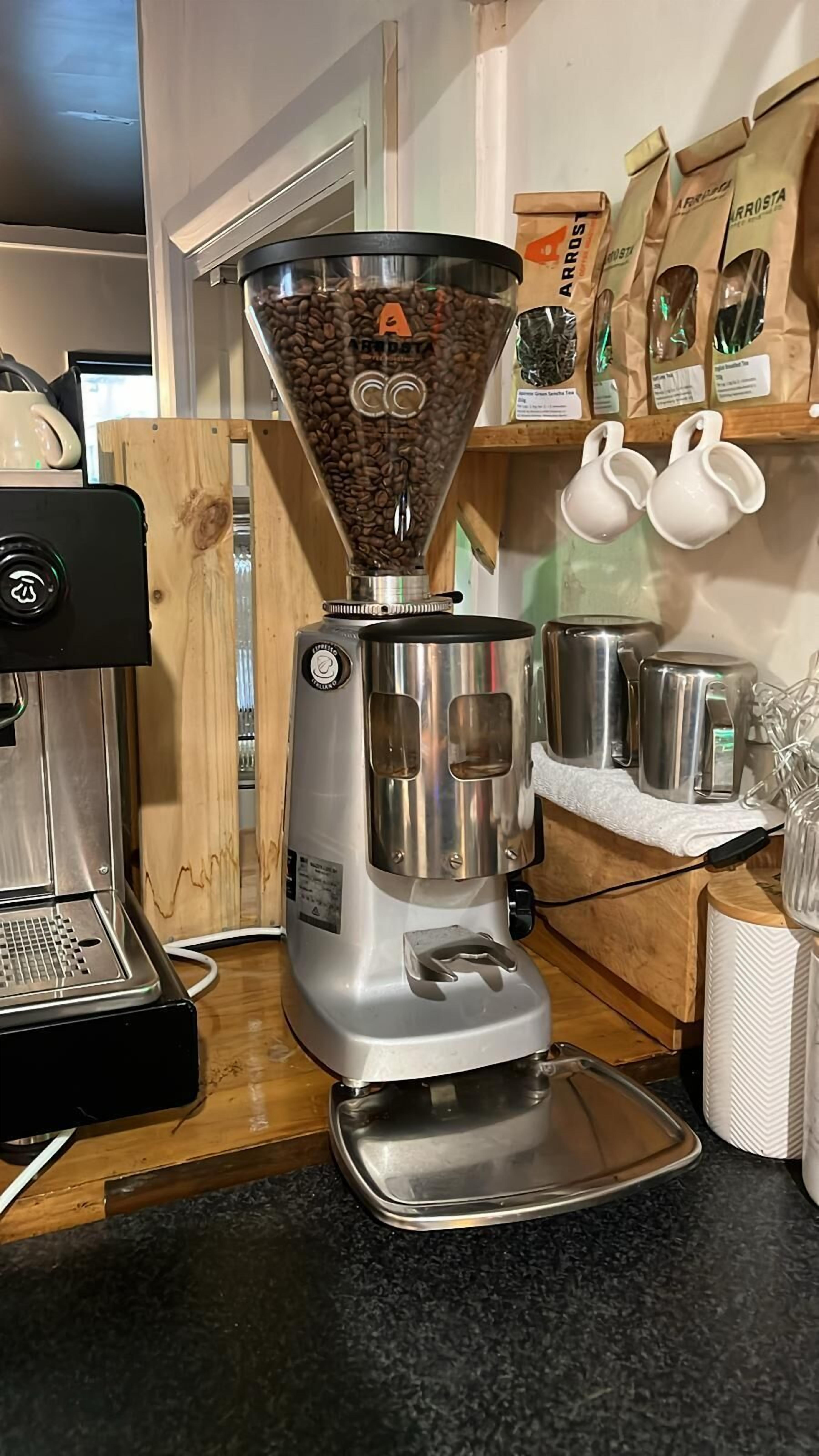 Una cafetera con molinillo integrado, una tetera y una jarra de café sobre una encimera de cocina.