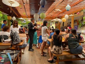A covered outdoor dining area with wooden tables and chairs, surrounded by greenery. - Peru Star Apart-Hotel (Lima)