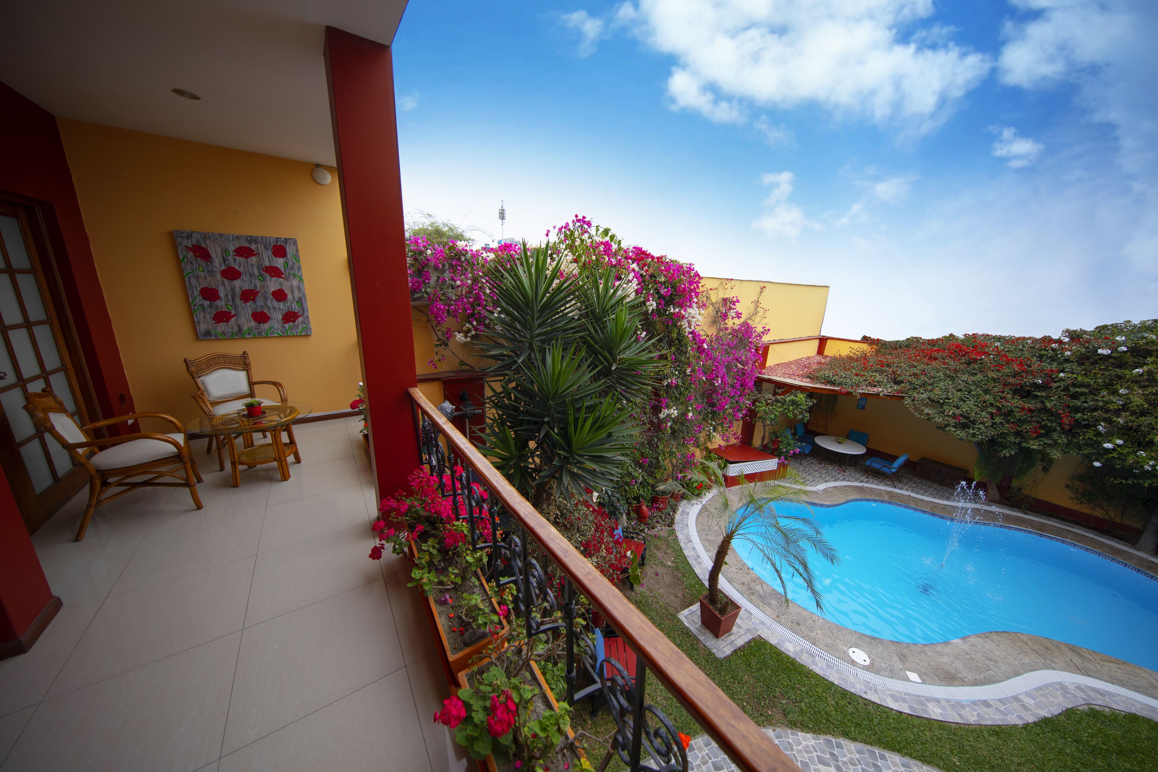 A pool area with a wooden deck, chairs, and a flower arrangement.