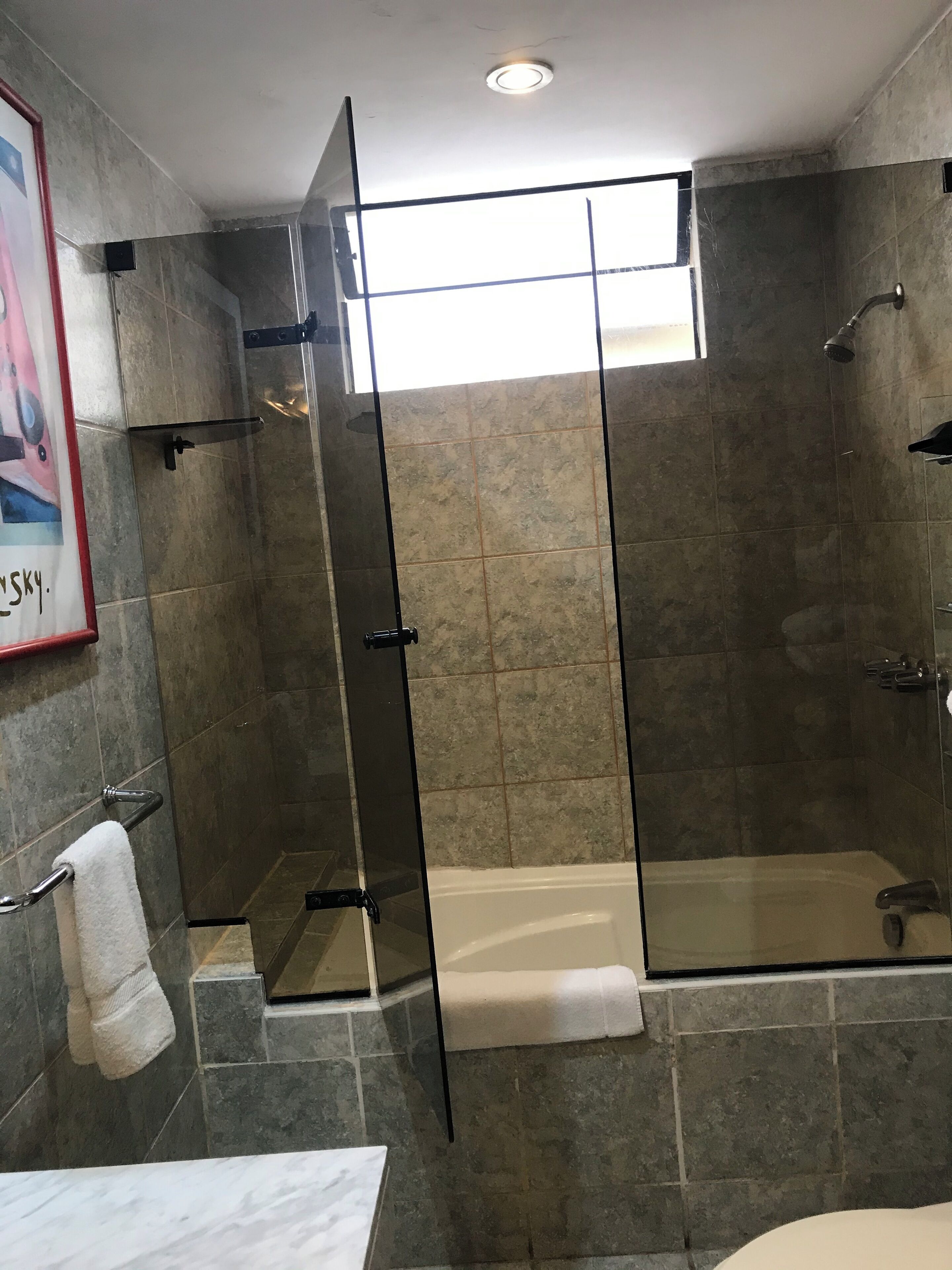 Un baño moderno con ducha envuelta en vidrio, una bañera y encimera de mármol.