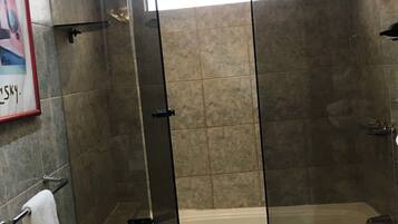 Un baño moderno con ducha envuelta en vidrio, una bañera y encimera de mármol.