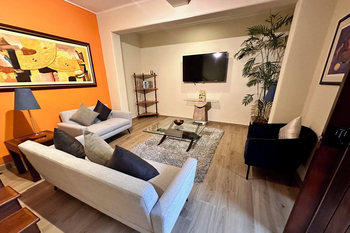 Una sala de estar con sofá, mesa de centro y televisor.