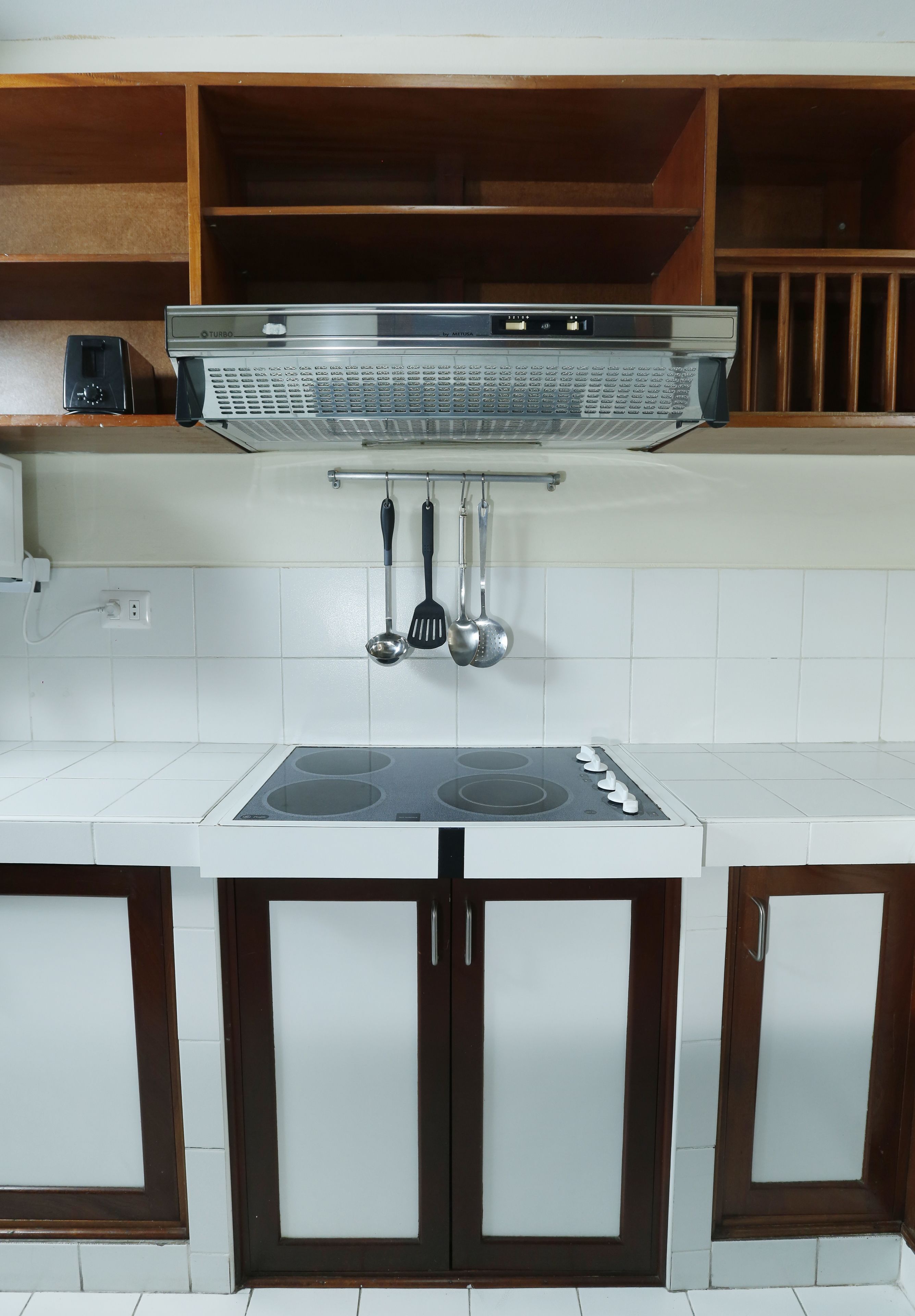A kitchen with a built-in stove, white cabinets, and wooden shelves.