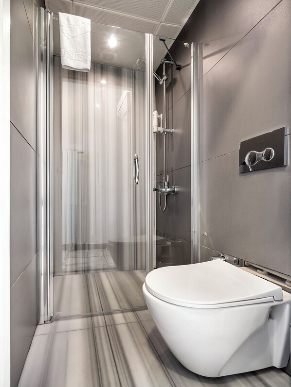 A modern bathroom with a glass-enclosed shower, a freestanding bathtub, and a towel rack. - The Pera Hotel (Istanbul)