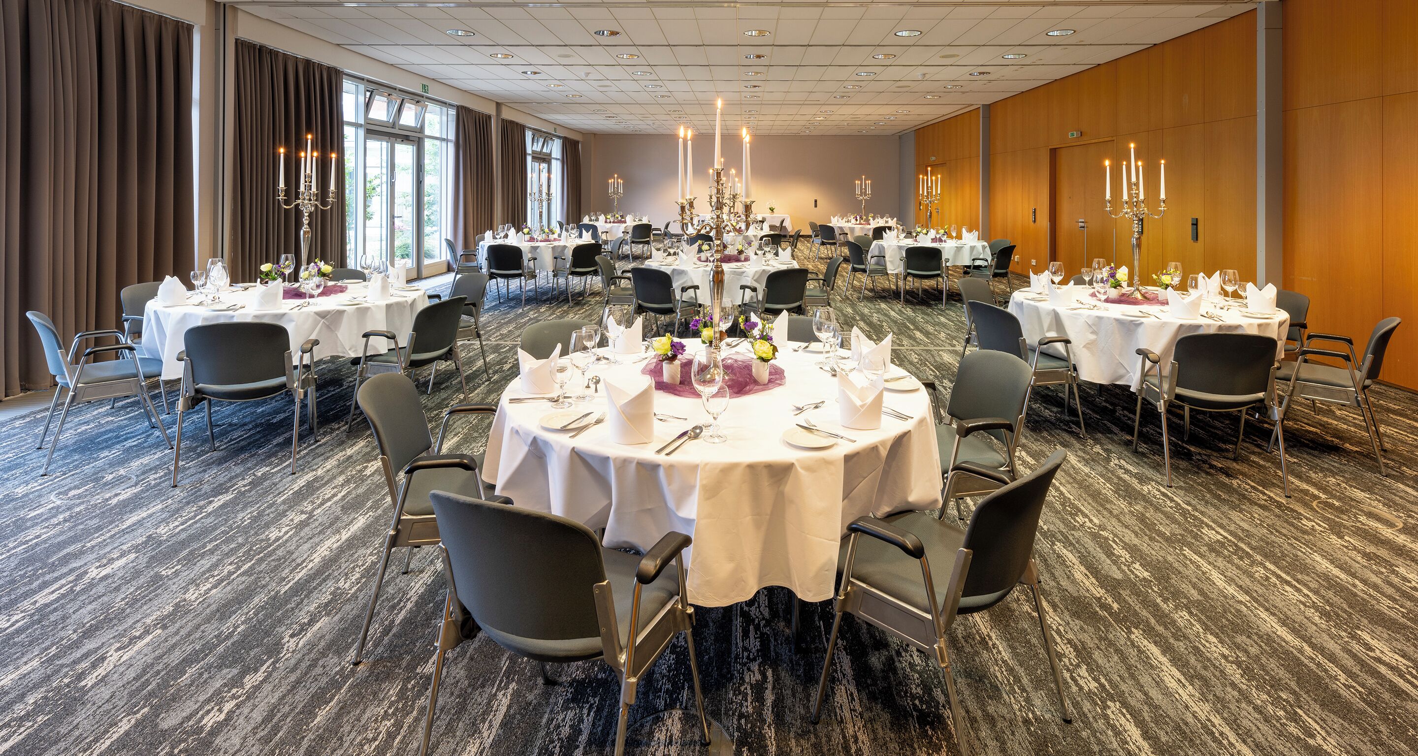 Un salón de banquetes con mesas redondas dispuestas para comer, organizadas en filas.