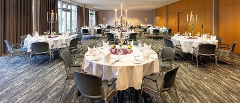 Un salón de banquetes con mesas redondas dispuestas para comer, organizadas en filas.