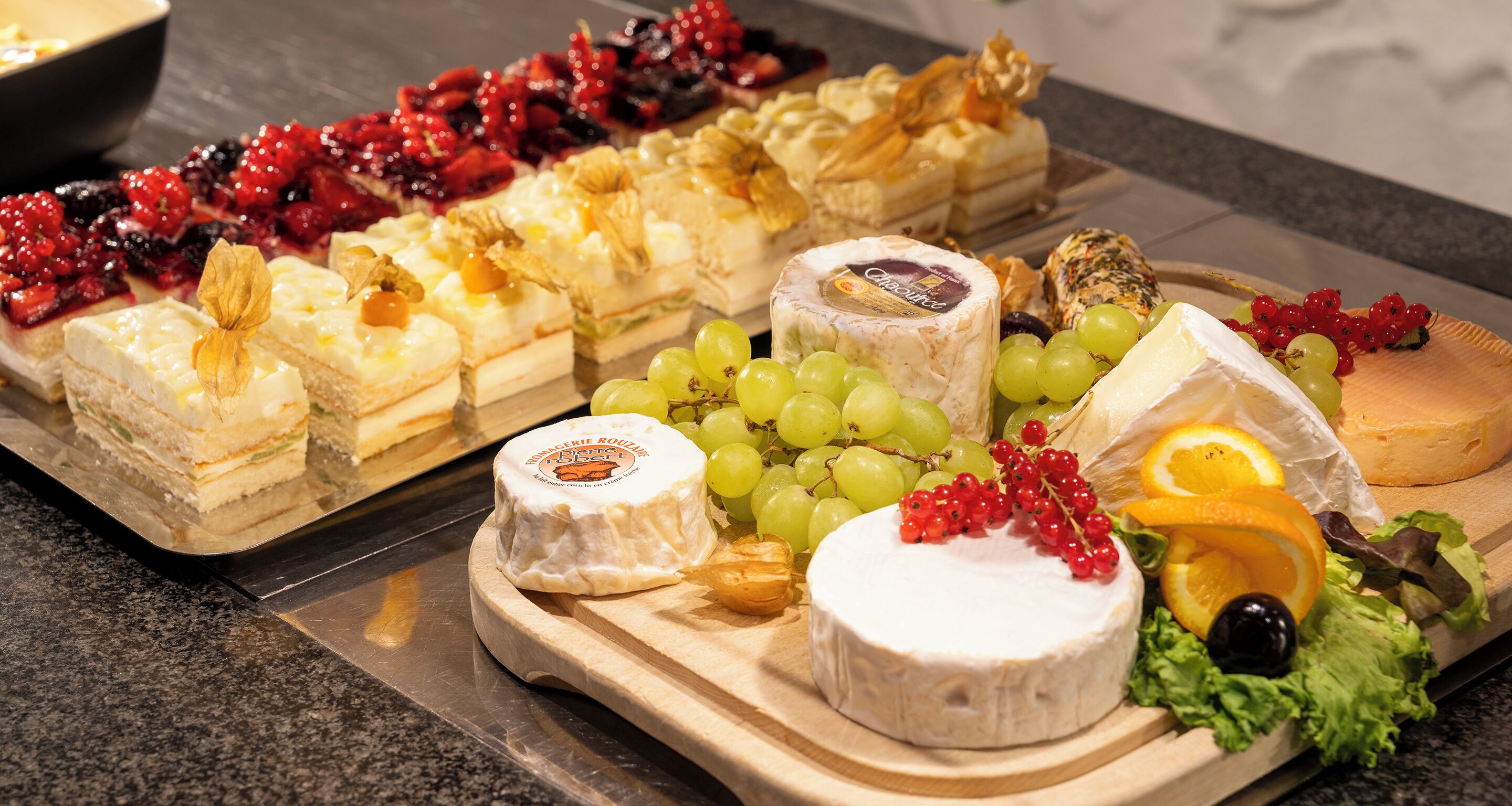 Una selección de quesos y frutas sobre una tabla de madera.