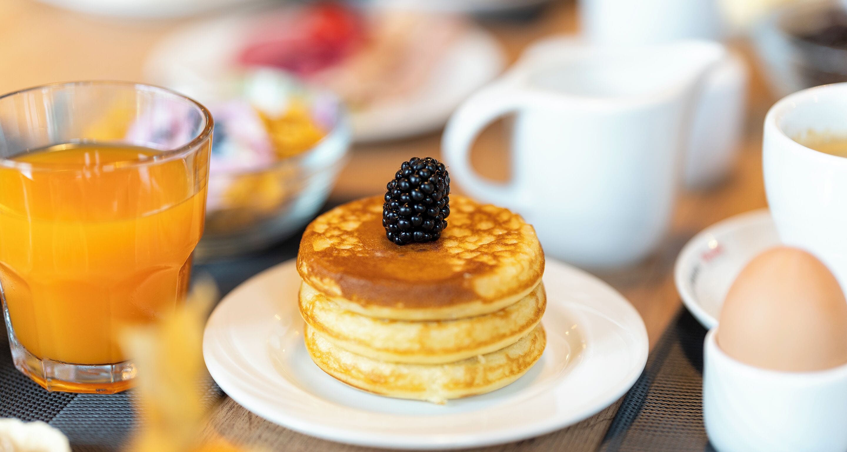 Desayuno con tortitas, un vaso de jugo de naranja y una taza de café.