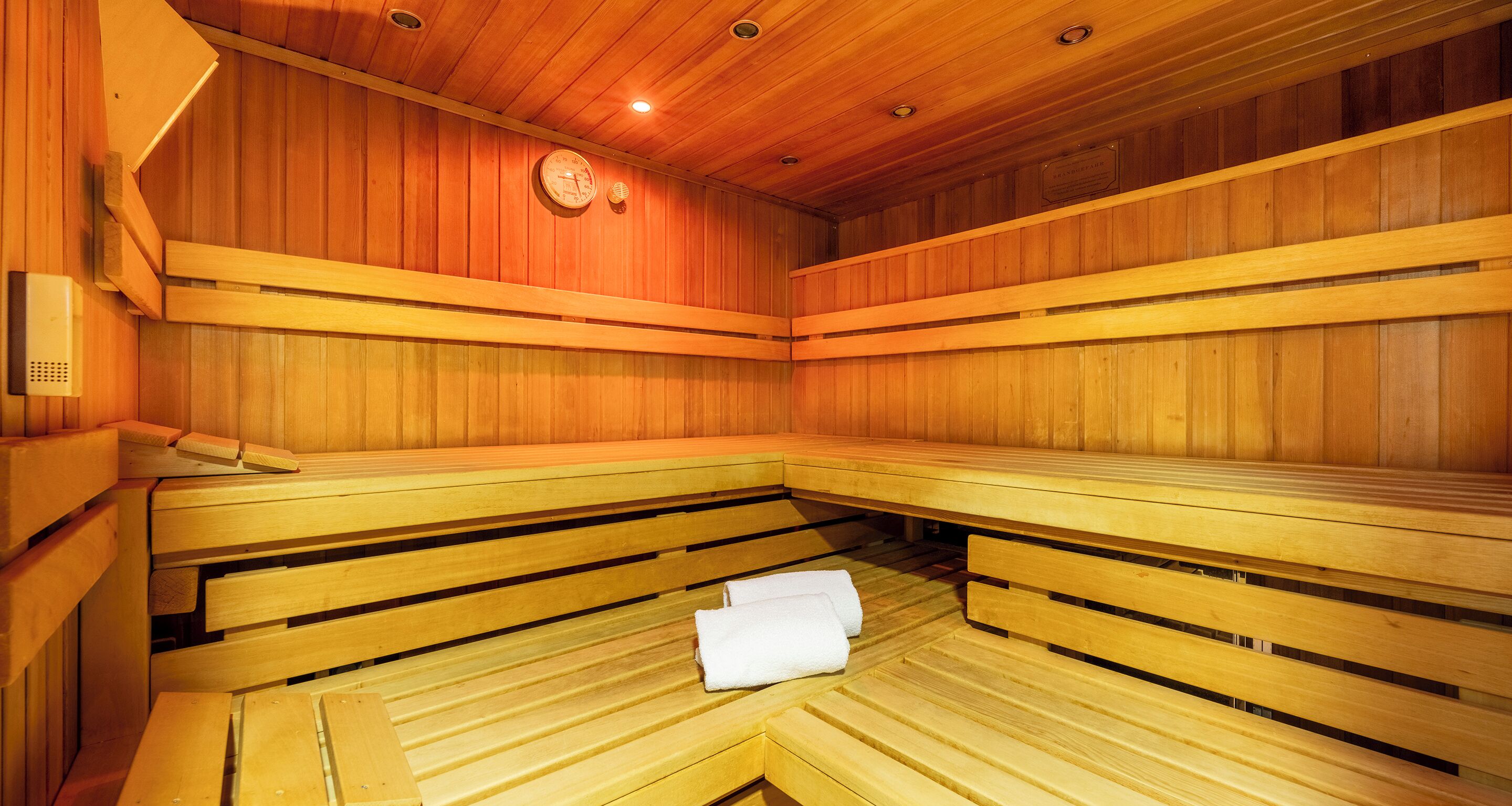 A sauna with wooden benches and a clock on the wall.