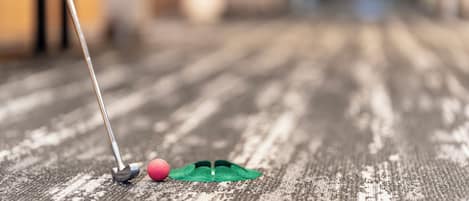 A close-up of a golf ball and club on a wooden surface.