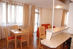 A dining area with a wooden table and chairs, a sofa, and a bar counter. - Elegant Lodge Hotel (Bansko)