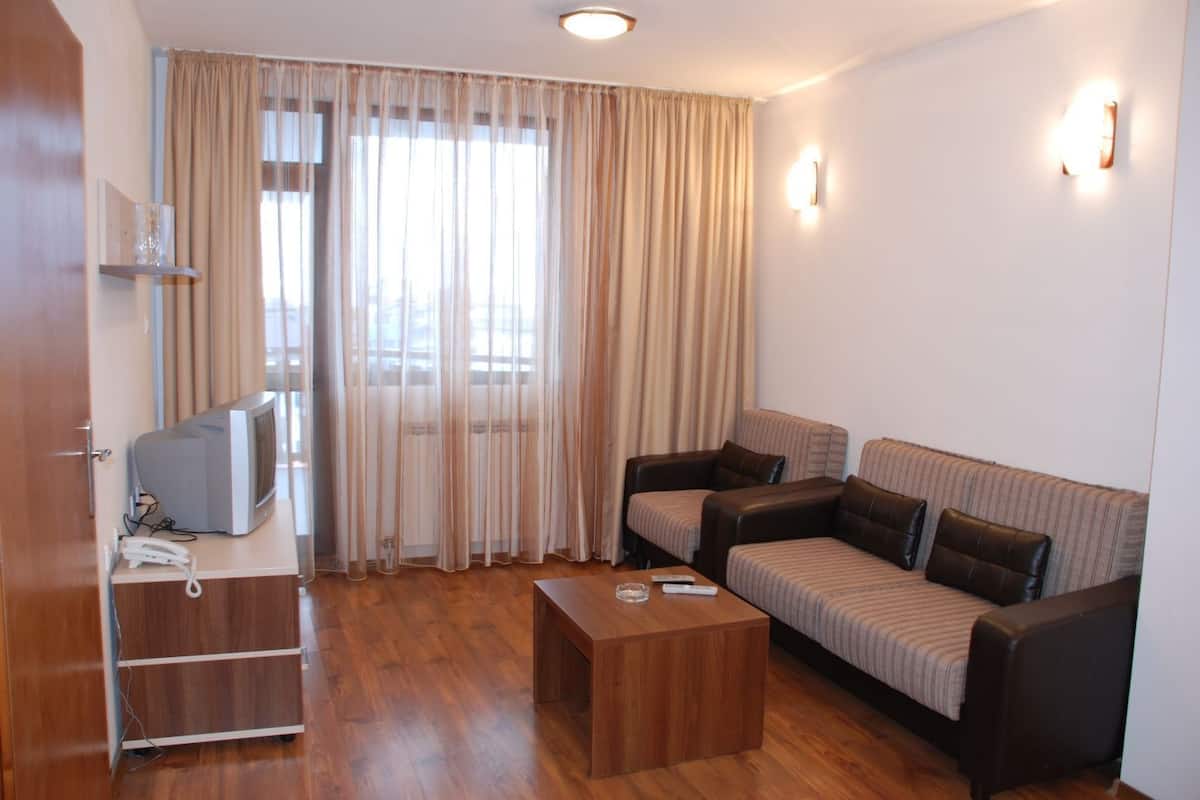 A living room with a sofa, a coffee table, and a television on a stand.