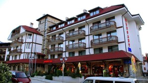 A multi-story hotel with balconies, a red awning, and a visible restaurant entrance. - Elegant Lodge Hotel (Bansko)