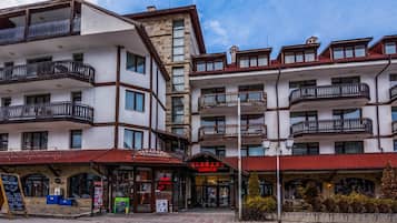Un hotel a più piani con balconi, un ristorante e un cartello che riporta 'Eugent Lodge'.