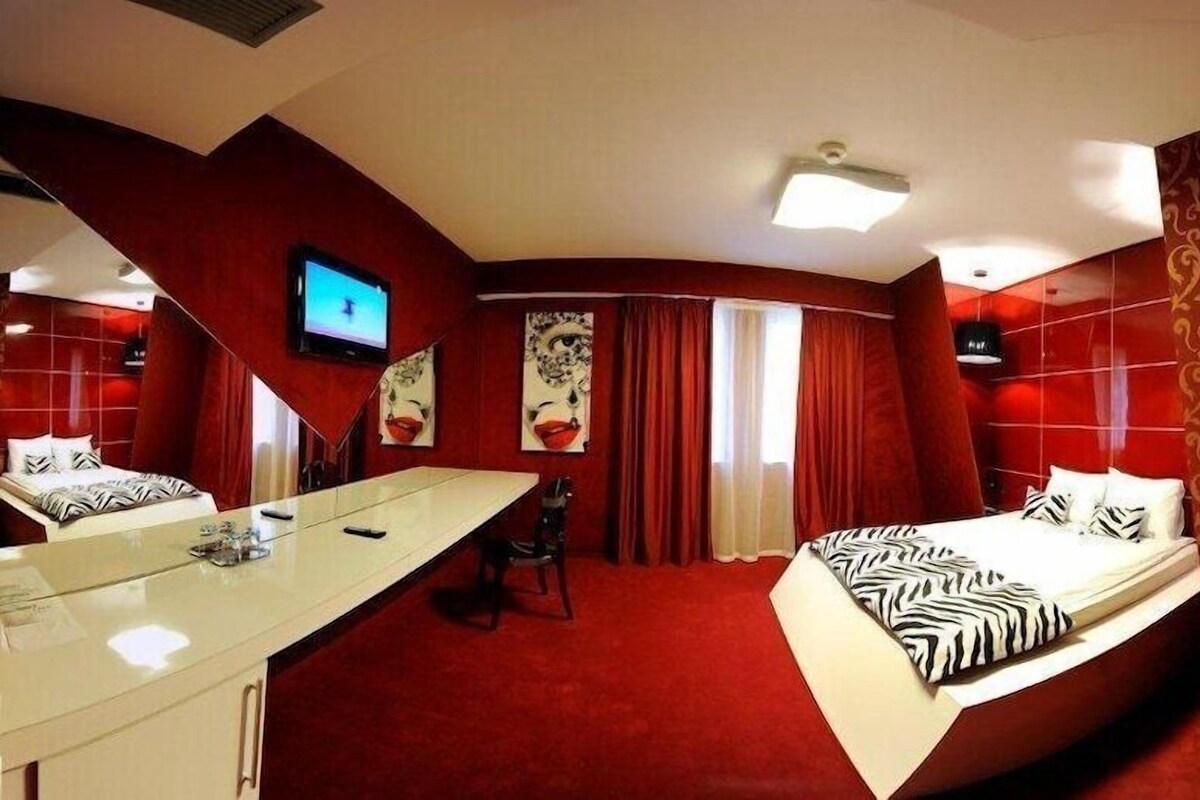 A hotel room with a bed, a desk, a chair, and a television.
