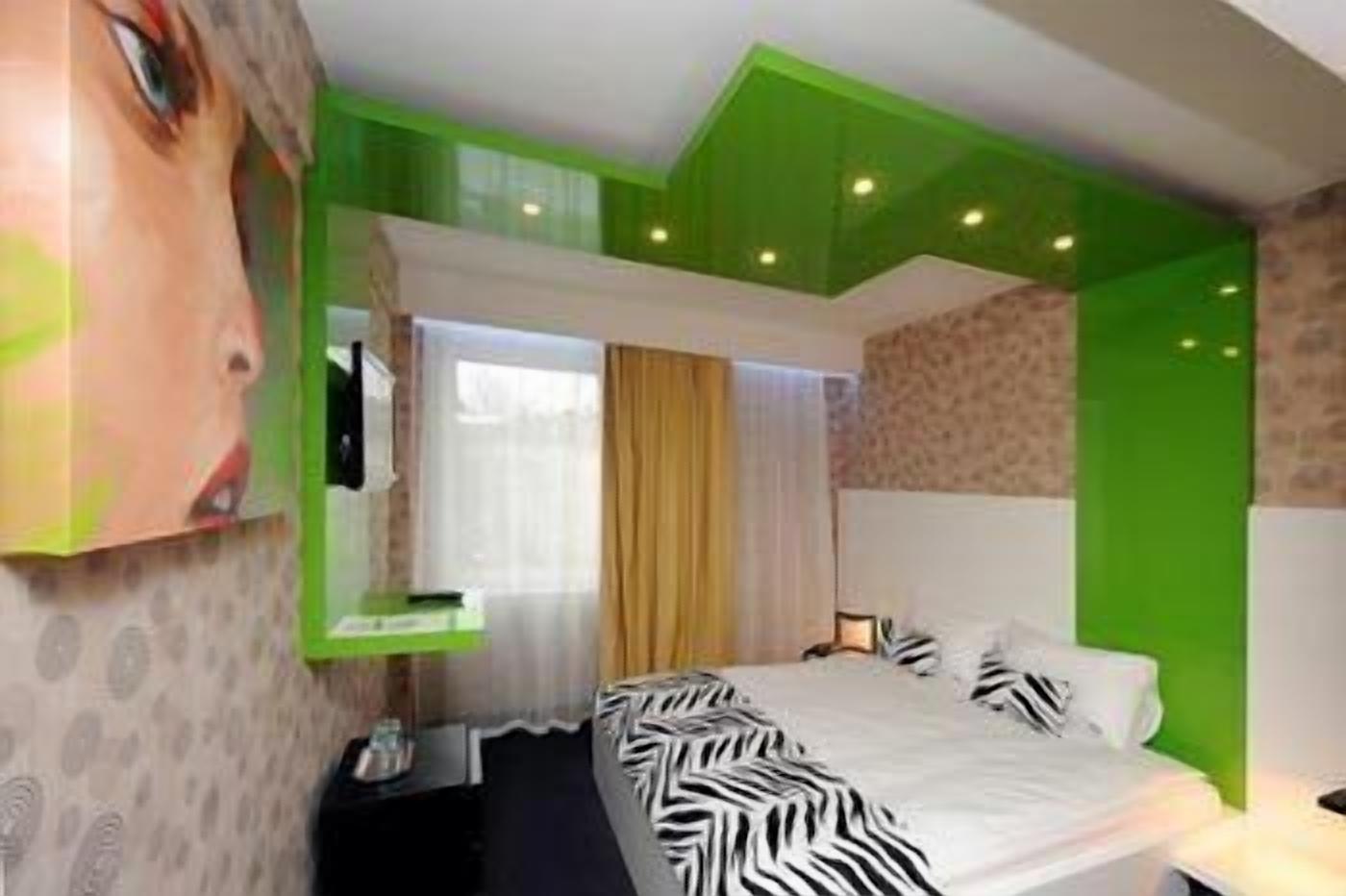 A modern bedroom with a zebra-patterned bedspread, a large mirror, and green accent walls.