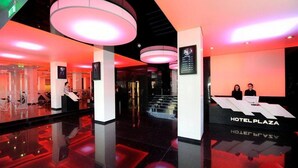 Un moderno vestíbulo de hotel con un diseño elegante, que incluye un mostrador de recepción, pantallas informativas digitales y un espacio amplio.