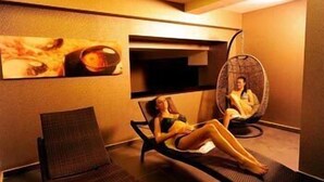 Un cuarto de spa con una silla de masaje, un sillón de relajación y una camilla de masaje fijada a la pared.
