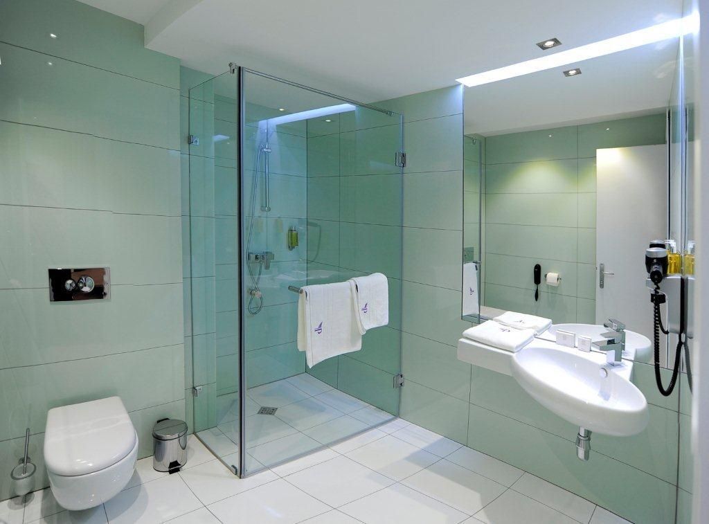 A modern bathroom with a glass shower enclosure, a toilet, and a sink with a mirror.