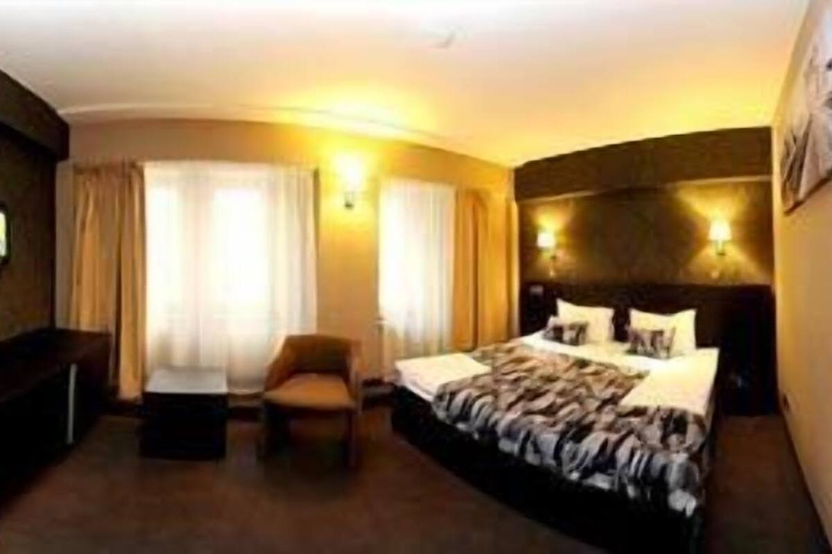 A hotel room with a bed, a desk, a chair, and a large mirror.