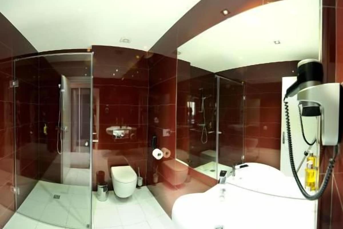 A modern bathroom with a glass-enclosed shower, a white bathtub, and a toilet.