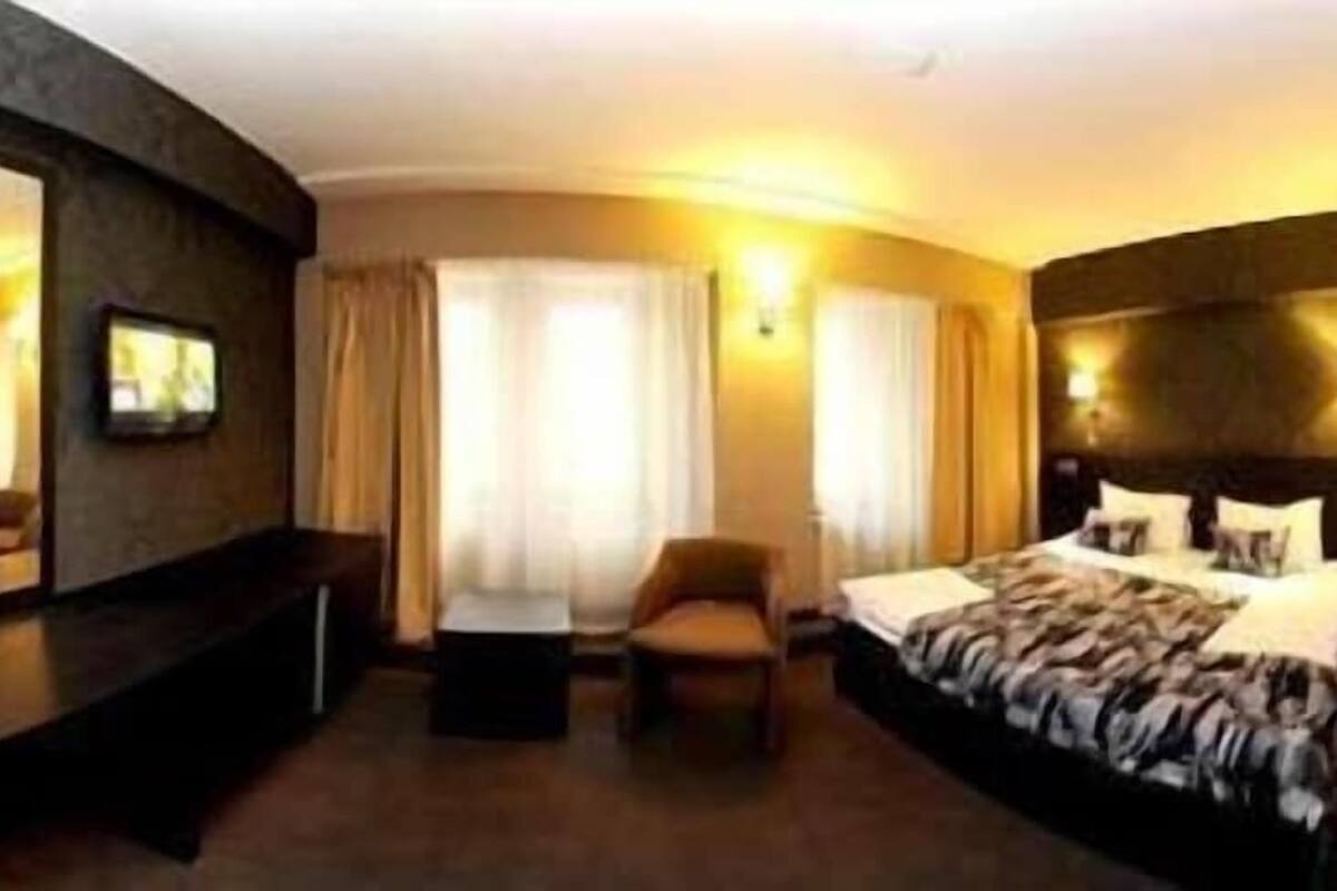 A hotel room with a bed, a desk, a chair, and a large mirror.