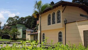 Uma casa de dois andares com fachada bege, janelas em arco e um pequeno alpendre.