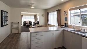 Una cocina moderna con una isla central, un área de comedor con sofá y mesa, y vistas al exterior a través de amplios ventanales.