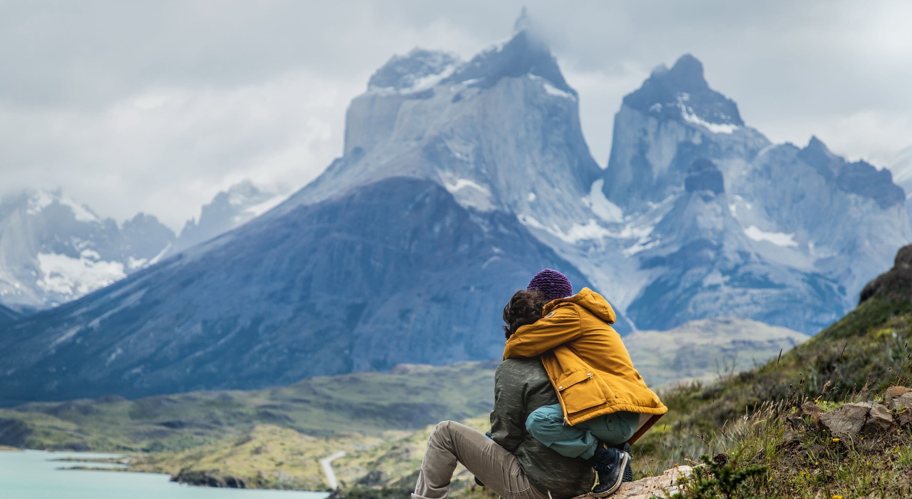A person sitting on a rock with a mountain view in the background.