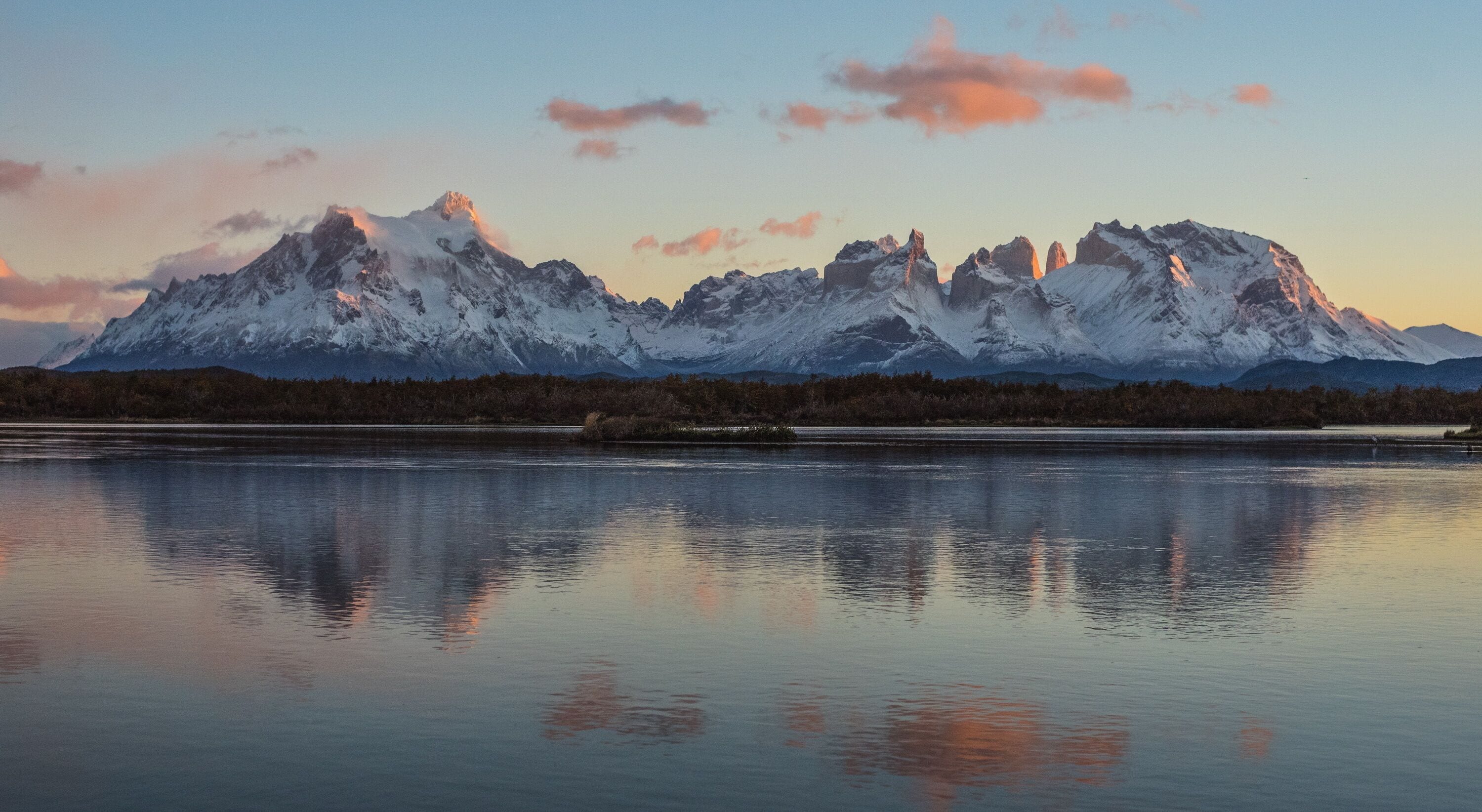 Ein Bergmassiv spiegelt sich bei Sonnenuntergang in einem ruhigen See.