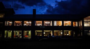 A multi-story building with illuminated windows and a dark sky.