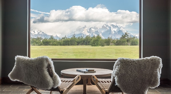 Una habitación con dos sillas frente a un ventanal que da a un paisaje montañoso.