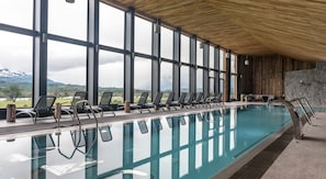 Piscina interior con vistas despejadas a un paisaje montañoso a través de amplios ventanales.